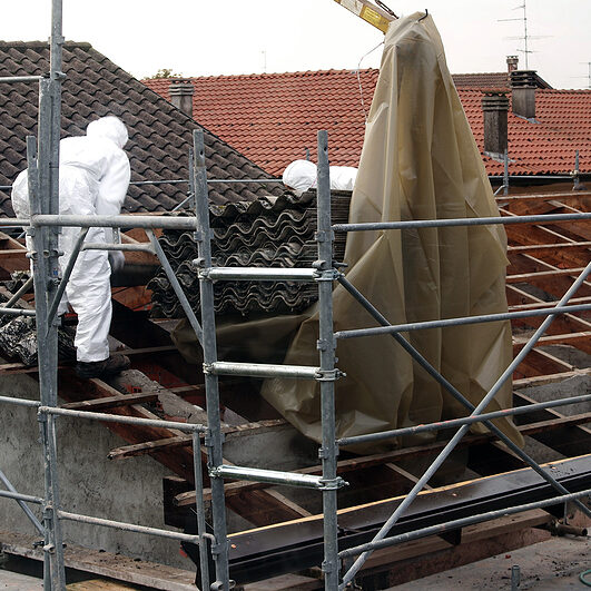 VAPRIO ITALY - NOVEMBER 7 2016: men at work on a roof of an old rural building removing asbestos panels