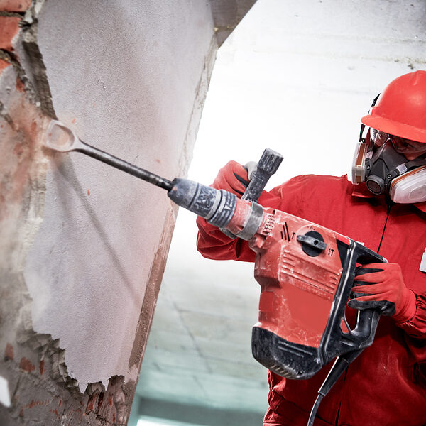 Demolition and construction destroying. worker with hammer breaking interior wall plastering