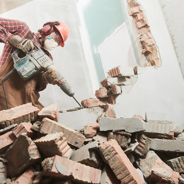 worker with demolition hammer breaking interior wall